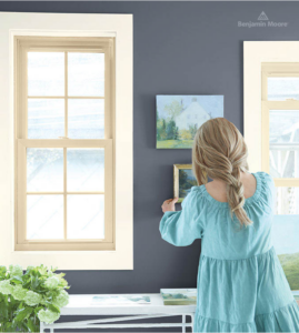 Woman hanging photos on wall painted Benjamin Moore Mysterious